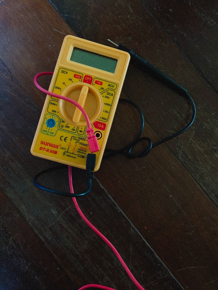 Home A digital multimeter with wires on a wooden surface, focused view.