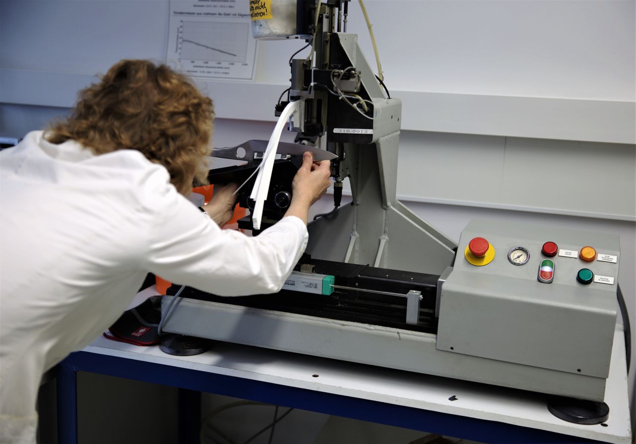 About Scientist operates a precision testing machine in a modern laboratory setting.